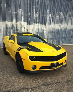 a yellow sports car parked in front of a metal building with graffiti on it's side