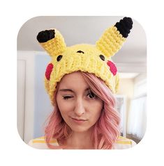 a woman with pink hair wearing a pikachu knitted hat in front of her face