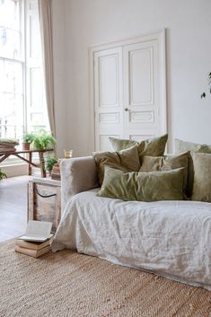 a living room filled with lots of pillows on top of a white couch next to a window