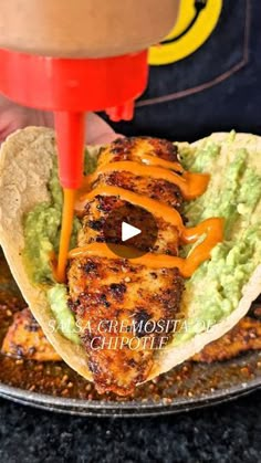 someone is pouring sauce on a chicken taco