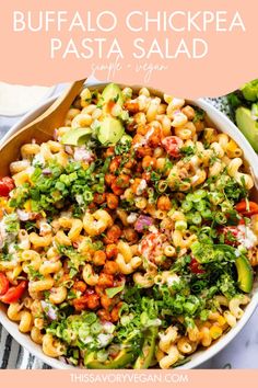 a bowl filled with pasta salad and topped with lettuce, tomatoes, avocado