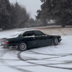 a black car driving down a snow covered road