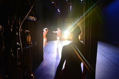 two people standing on a stage in front of a camera and some lights behind them