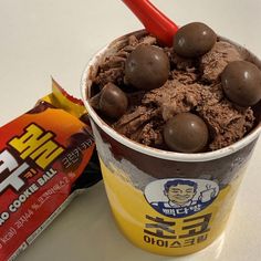 a cup filled with chocolate ice cream next to a bar of chocolate chips and a candy bar