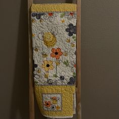 a towel hanging on the wall next to a wooden rack with an orange and yellow flower design