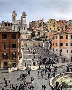 many people are walking up and down the stairs in an old european city with tall buildings