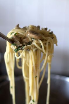 a spoon full of noodles with mushrooms and spinach