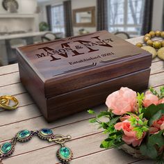 a wooden box sitting on top of a table next to some flowers and other jewelry