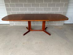 a wooden table sitting in front of a brick wall with a white garage door behind it