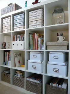 an organized bookcase with many bins and boxes on the bottom shelf in front of it