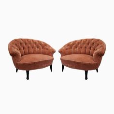 a pair of brown velvet chairs with black legs and tufted cushions, on white background