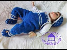 a baby doll laying on top of a white bed next to a blue and white blanket