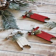 three red and white popsicle christmas ornaments on a wooden table next to pine cones