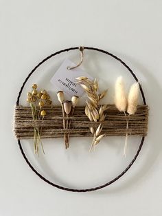 an arrangement of dried flowers and twigs on a circular piece of wood hanging from a wall