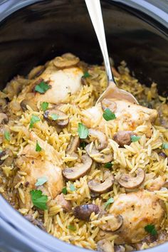 chicken and mushroom rice in a crock pot with a spoon sticking out of it