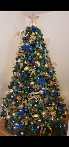 a christmas tree is decorated with blue, green and gold ornaments