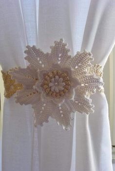 a white curtain with crocheted flowers on it