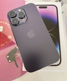 an iphone 11 pro sitting on top of a pink disc next to it's packaging