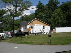 a house being built in the middle of a yard with lots of grass and trees