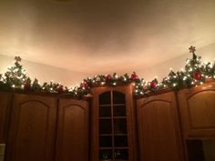 christmas lights on the top of cabinets in a room with wooden floors and ceilinging