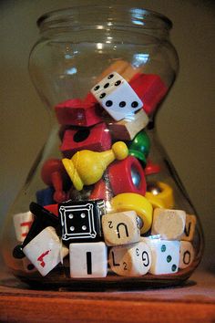 a glass vase filled with lots of different types of dice