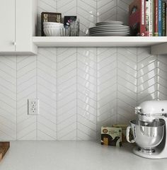 a kitchen counter with a mixer, books and other items on the shelves above it