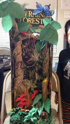 a young boy standing next to a fake forest