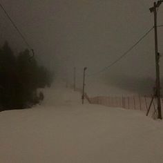 a person riding skis down a snow covered slope at a ski resort on a cloudy day