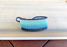 a blue and white basket sitting on top of a wooden table