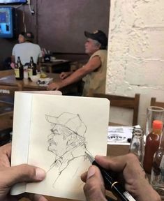 two people sitting at a table and one is drawing