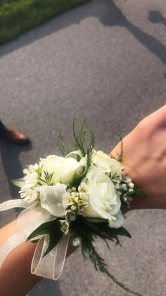 a bouquet of white flowers is being held by someone's hand on the street