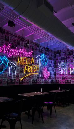 neon signs are on the wall behind tables and chairs in a restaurant with purple lighting