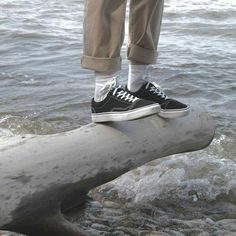 a person standing on top of a log in the water with their feet propped up