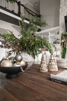 a wooden table topped with christmas trees and ornaments next to a book on top of a hard wood floor