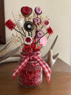 a jar filled with buttons and flowers on top of a table