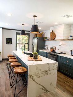 a kitchen with marble counter tops and stools in front of an island that's surrounded by wood flooring