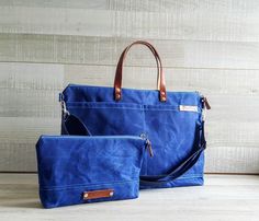 two blue bags sitting next to each other on a wooden floor with a white wall behind them