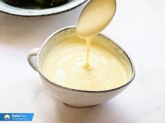 a spoon is pouring sauce into a bowl