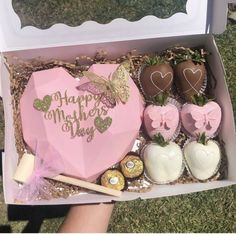 a box filled with chocolate covered strawberries and other treats on top of green grass