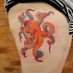 an orange octopus tattoo on the back of a woman's thigh with blue and pink flowers