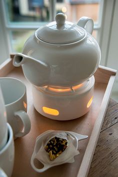 a white tea pot sitting on top of a wooden tray