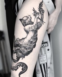 a woman's leg with a bear and flower tattoo design on it, in black and white