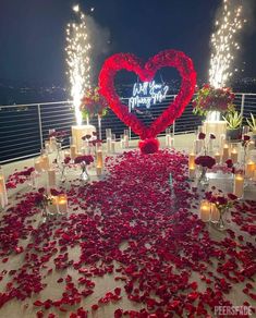 a heart - shaped table with candles and rose petals on it is set up for a wedding