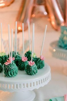 there are many green desserts on the cake platter with white sticks sticking out of them