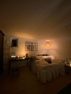 a dimly lit room with a bed, desk and pictures on the wall above it