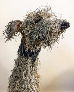 a sculpture of a dog with long hair and wearing a blue scarf on it's head