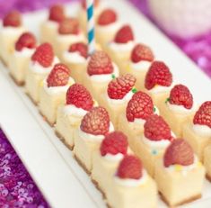 small desserts with raspberries are arranged on a white plate and purple table cloth