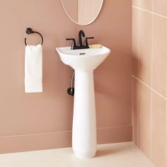 a white sink sitting next to a mirror and a towel hanging on a hook in a bathroom