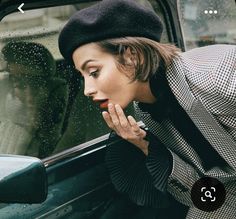 a woman leaning out the window of a car while holding her hand to her mouth