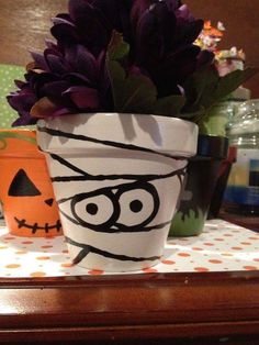 two potted plants decorated with faces and pumpkins are sitting on a table next to each other